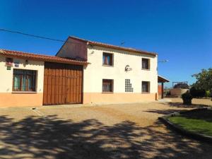 a large white house with a wooden garage at La huerta El Tordo in Manganeses de la Lampreana