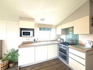 a kitchen with white cabinets and a sink and a stove at Grand Horizon in Hunmanby