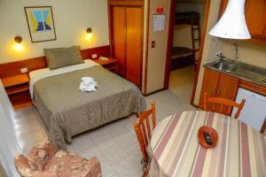 Un dormitorio con una cama y dos sillas y una mesa. en Valor inacreditável para Ano Novo com vista e perto de tudo, en Gramado