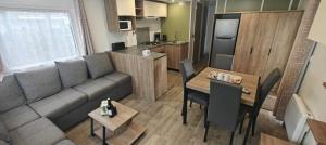 a living room and kitchen with a couch and a table at MH310 2 chambres et 2 salles de bain de 40m2 dans camping 4 étoiles in Saint-Julien-en-Born