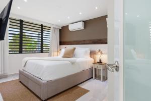 a white bedroom with a bed and a window at Villa Layka Beach House at Playas del Yunque in Rio Grande +31 photos