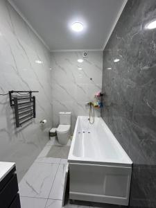 Un baño blanco con bañera y inodoro. en 3 комнатный апартамент на Батыс 2, en Aktobe