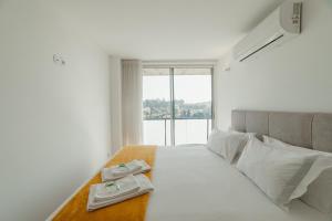 a bedroom with a white bed with a large window at Amazing Pool Apartments by Vacationy in Vila Nova de Gaia +40 photos