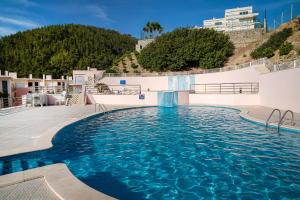 une piscine à l'eau bleue dans un immeuble dans l'établissement Vila das Conchas - Enjoy the Seaview Pool with the Beach only steps away, à Sesimbra