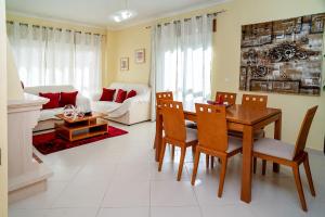 un salon avec une table, des chaises et un canapé dans l'établissement Vila das Conchas - Enjoy the Seaview Pool with the Beach only steps away, à Sesimbra
