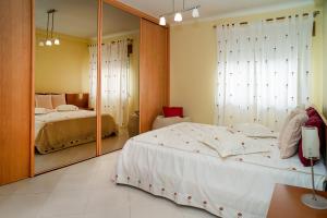 une chambre avec un grand lit et un miroir dans l'établissement Vila das Conchas - Enjoy the Seaview Pool with the Beach only steps away, à Sesimbra 30 autres photos