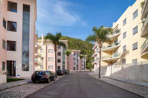 une rue dans une ville avec des palmiers et des bâtiments dans l'établissement Vila das Conchas - Enjoy the Seaview Pool with the Beach only steps away, à Sesimbra