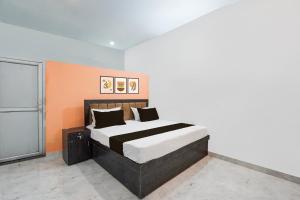 a bedroom with a bed with an orange wall at Hotel O Raj Family Restaurant & Hotels in Mahmūdnagar