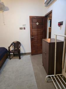 une chambre avec un lit, une armoire en bois et une chaise dans l'établissement Kubera Heritage Inn , Near Sreepadmanabhaswamy temple, à Trivandrum