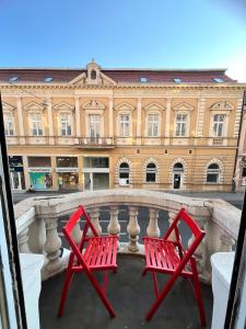 Dos sillas rojas sentadas en un balcón frente a un edificio. en Apartment Ksenija, en Belgrado 20 fotos más