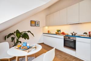 a kitchen with white cabinets and a table and chairs at SEEGER Living Premium Downtown in Karlsruhe