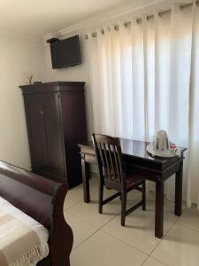 a bedroom with a desk and a telephone and a bed at Xintu Xa Hina Guesthouse in Nkowakowa