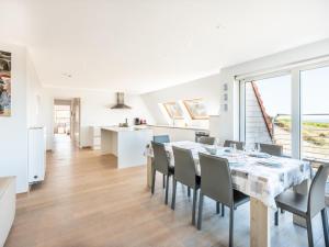 a white kitchen and dining room with a table and chairs at Seawhisper in Galopen