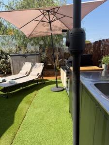 a patio with an umbrella and two chairs and a grill at The Retreat - Armacao de Pera, Algarve Portugal in Pêra