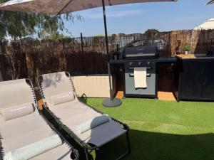 a patio with a grill and two chairs and an umbrella at The Retreat - Armacao de Pera, Algarve Portugal in Pêra