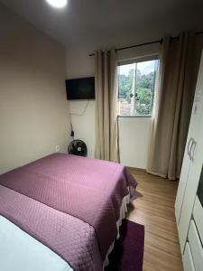une chambre avec un lit violet et une fenêtre dans l'établissement Espaço Tavares Ouro Preto-MG, à Água Boa