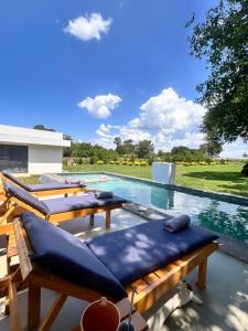una piscina con sillas acolchadas azules junto a una piscina en Casa Blanca, en Asunción 17 fotos más