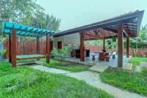 un padiglione in un giardino con una panchina e dei tavoli di Canto dos Pássaros a Itacaré