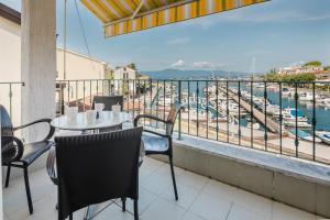 Un balcón con mesa y sillas y vista a un puerto deportivo. en Apartments Obala, en Malinska