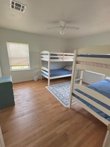 a bedroom with two bunk beds and a wooden floor at Paradise Surf House in Galveston