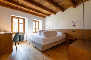 ein Schlafzimmer mit einem Bett, einem Schreibtisch und Fenstern in der Unterkunft La Corte del Glicine in Villa di Tirano