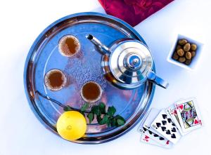 a glass dish with a pot of coffee on a table with playing cards at Maison D'hôtes Ait Mouli in Bzou