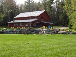 a red barn in front of a green field at Robert Frost Mountain Cabins in Middlebury