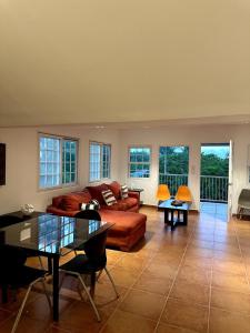 een woonkamer met een bank, tafels en ramen bij Casa Kitesurf - 1 Min a Playa, Pool, BBQ in Chame