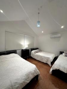 twee bedden in een kamer met witte muren bij Casa Kitesurf - 1 Min a Playa, Pool, BBQ in Chame