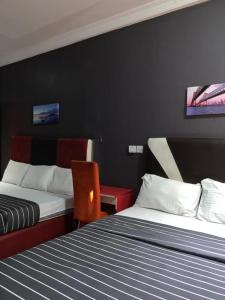 a hotel room with two beds and a chair at Pulville Boulevard Hotel in Surulere +19 photos