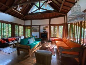 a living room with couches and tables and windows at Casa Sertão de Camburi in Camburi