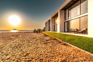 a house on the beach with the sunset in the background at Dolphin View Beach House in Walvis Bay