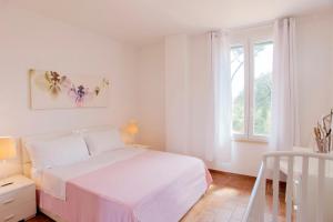 a white bedroom with a bed and a window at Tenuta le marze in Castiglione della Pescaia