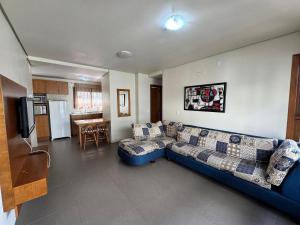 un soggiorno con un divano blu e una cucina di Apê Novo Centro de Gramado 02 dorm a Gramado