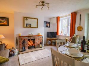 a living room with a table and a fireplace at Poppy Cottage in Charlton Marshall