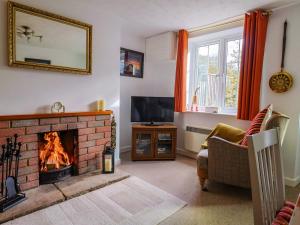 a living room with a fireplace and a tv at Poppy Cottage in Charlton Marshall