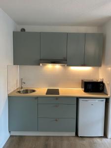 a kitchen with white cabinets and a sink and a microwave at Le Belvédère - Balcon plein sud au calme in Saint-Pierre-du-Mont