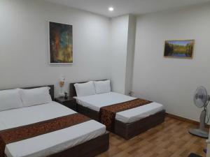 a room with two beds and paintings on the wall at Nhà nghỉ 79 in Ðình Loan