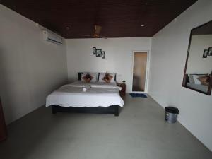 a bedroom with a bed in a white room at Colomb Beach Huts in Patnem