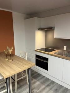 a kitchen with white cabinets and a wooden table at Le Refuge du Cerf in Bouillon