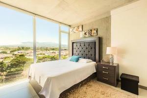 Un dormitorio con una cama grande con una ventana grande. en Studio Panorámico en la Ciudad, en Curridabat
