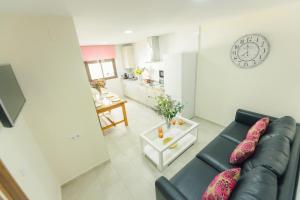 a living room with a black leather couch and a kitchen at Casa Pepi Sánchez Conil in Conil de la Frontera