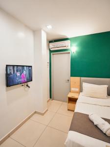 a room with two beds and a tv on the wall at Eco Roomy Hotel in Kuala Lumpur
