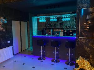 a bar with purple lighting in a room with stools at Magical Desire in Bragadiru