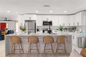 une cuisine avec des armoires blanches et des tabourets de bar dans l'établissement 5BR Family Pool Villa By Eagle Park, à Clearwater