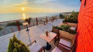 a deck with tables and chairs on the beach at White Home & Garden in Klaipėda