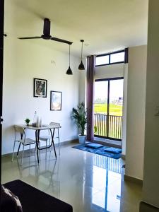 a living room with a table and a balcony at Saya's Abode - Railview Suites in Tezpur