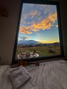 a guitar sitting on a bed in front of a window at Tiny Glamp House - DANGUBA by IGLENA in Kupres