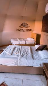 two beds in a room with a sign on the wall at FARAH RUM LUXURY CAMP & Bubbles Hotel in Wadi Rum
