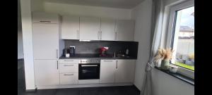 eine Küche mit weißen Schränken und einer Spüle und einem Fenster in der Unterkunft M&M AusZeit im Schwabenländle in Winterlingen